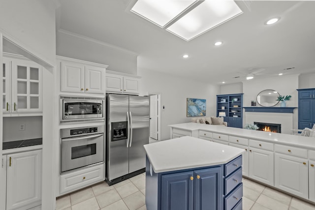 kitchen featuring blue cabinetry, appliances with stainless steel finishes, white cabinetry, a kitchen island, and light tile patterned flooring