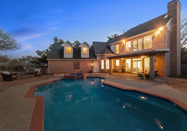 pool at dusk with a patio area and an in ground hot tub