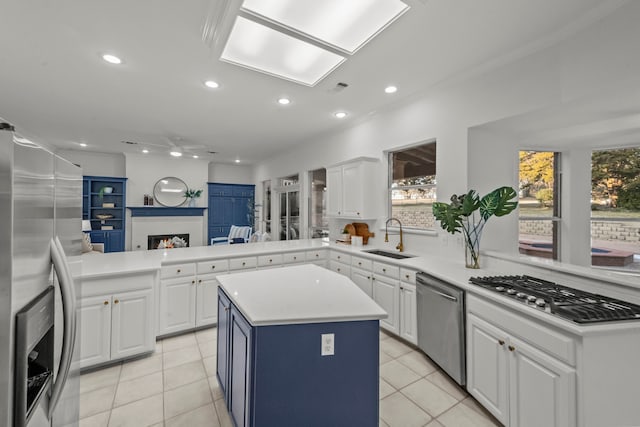 kitchen featuring a kitchen island, white cabinetry, sink, kitchen peninsula, and stainless steel appliances