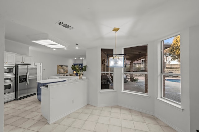 kitchen with white cabinetry, appliances with stainless steel finishes, kitchen peninsula, and a wealth of natural light