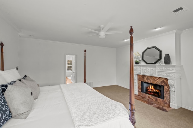 bedroom featuring connected bathroom, crown molding, carpet, ceiling fan, and a premium fireplace