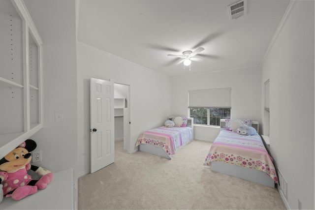 carpeted bedroom with crown molding, a spacious closet, and ceiling fan