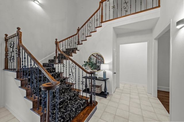 stairway featuring tile patterned flooring and a high ceiling