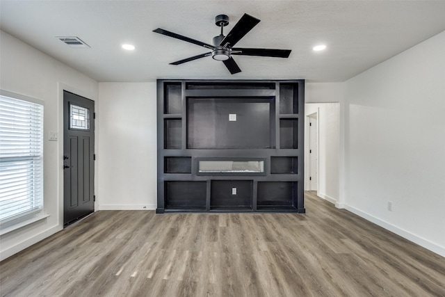 unfurnished living room with ceiling fan, wood-type flooring, and a healthy amount of sunlight