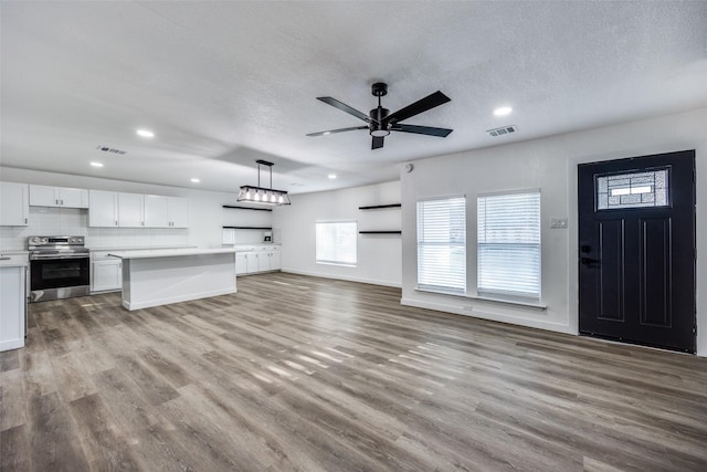 unfurnished living room with ceiling fan, a textured ceiling, and light hardwood / wood-style flooring