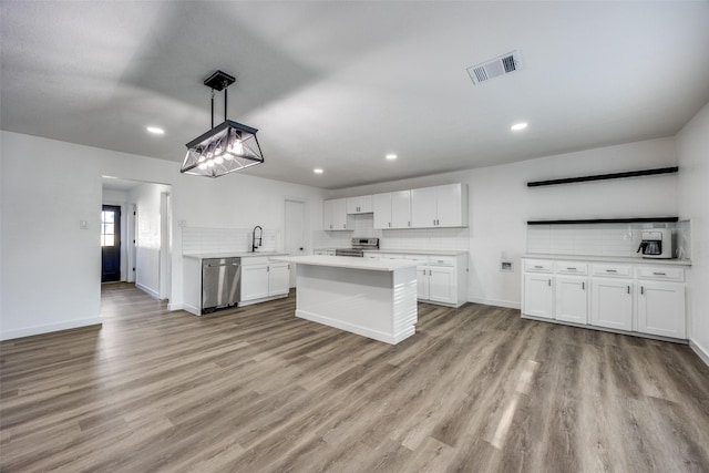 kitchen featuring hanging light fixtures, light hardwood / wood-style flooring, white cabinetry, and stainless steel appliances