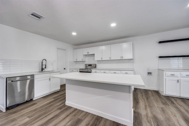 kitchen featuring light hardwood / wood-style floors, a center island, sink, appliances with stainless steel finishes, and white cabinets