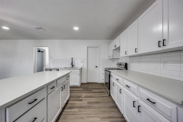 kitchen with backsplash, dark hardwood / wood-style floors, sink, white cabinetry, and stainless steel range with electric cooktop