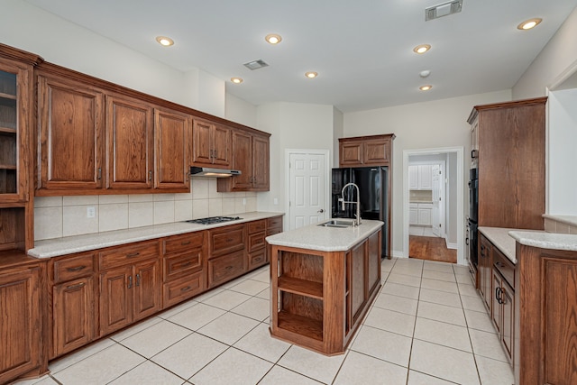 kitchen with sink, gas stovetop, light tile patterned floors, a kitchen island with sink, and decorative backsplash