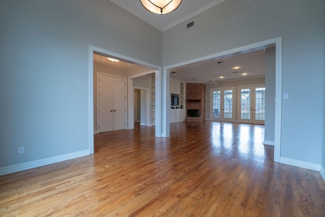 unfurnished living room with crown molding, ceiling fan, a fireplace, and light wood-type flooring