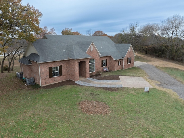 view of front of house with central AC unit and a front lawn