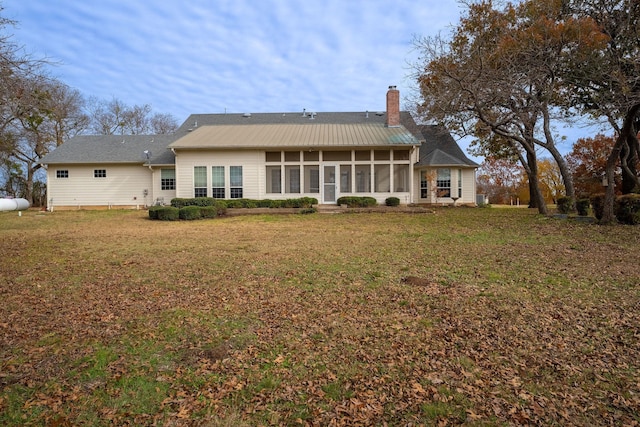 back of property with a sunroom and a yard