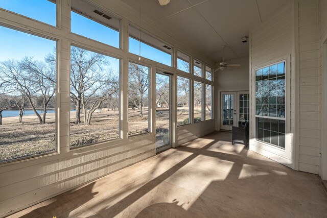 unfurnished sunroom featuring a water view and ceiling fan