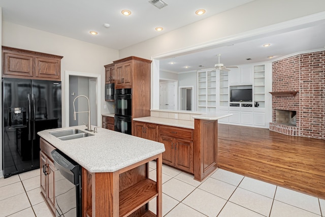 kitchen featuring light tile patterned flooring, sink, an island with sink, and black appliances