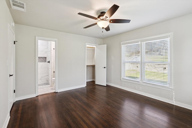 unfurnished bedroom featuring ceiling fan, dark hardwood / wood-style floors, connected bathroom, a walk in closet, and a closet