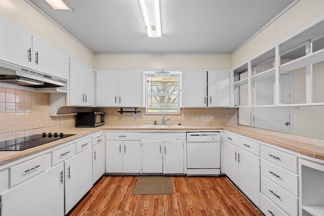 kitchen featuring white dishwasher, white cabinetry, black electric stovetop, and decorative backsplash