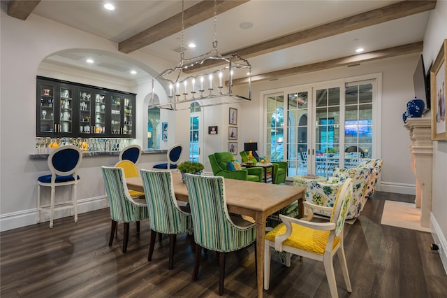 dining space with dark wood-type flooring, bar area, a chandelier, and beamed ceiling