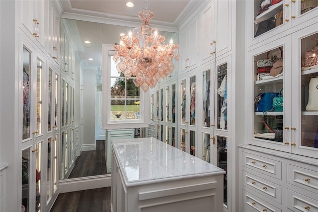 walk in closet with dark wood-type flooring and a notable chandelier