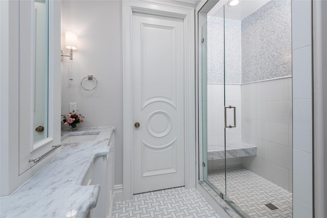 bathroom featuring a shower with shower door and vanity