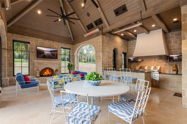 dining area with an outdoor stone fireplace, wood ceiling, ceiling fan, high vaulted ceiling, and beam ceiling