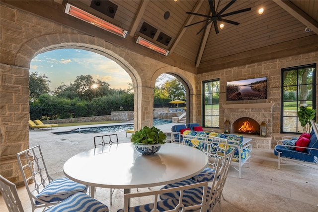 view of patio / terrace featuring ceiling fan, an outdoor stone fireplace, and an indoor pool