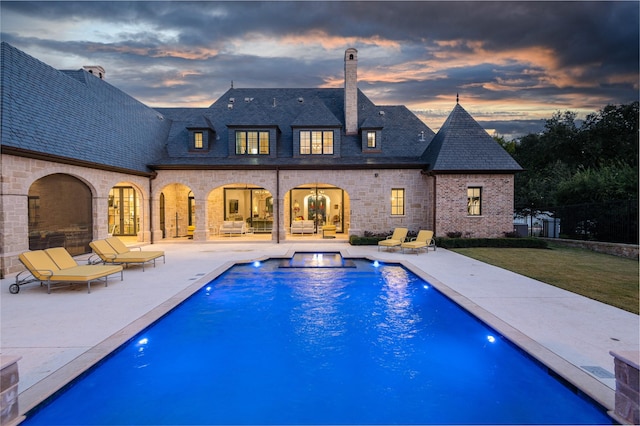 pool at dusk with a yard and a patio