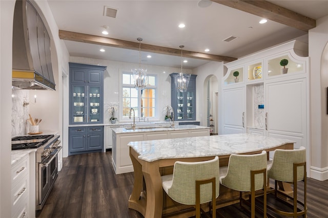 kitchen featuring pendant lighting, a center island, dark wood-type flooring, range with two ovens, and an inviting chandelier