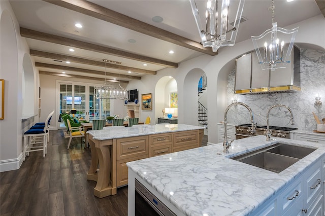 kitchen with a kitchen island with sink, light stone countertops, and pendant lighting