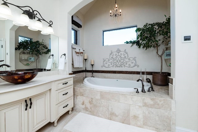 bathroom with tiled bath, vanity, and a chandelier