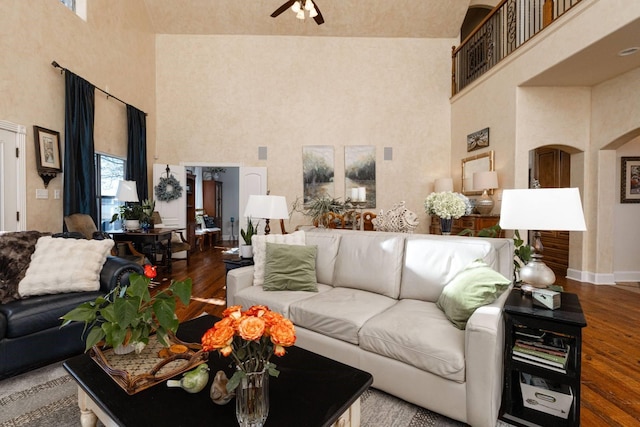 living room with ceiling fan, hardwood / wood-style floors, and a high ceiling