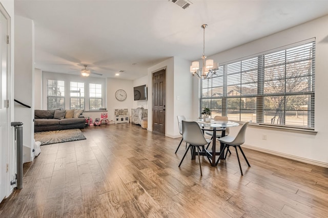 dining space featuring ceiling fan with notable chandelier and hardwood / wood-style floors