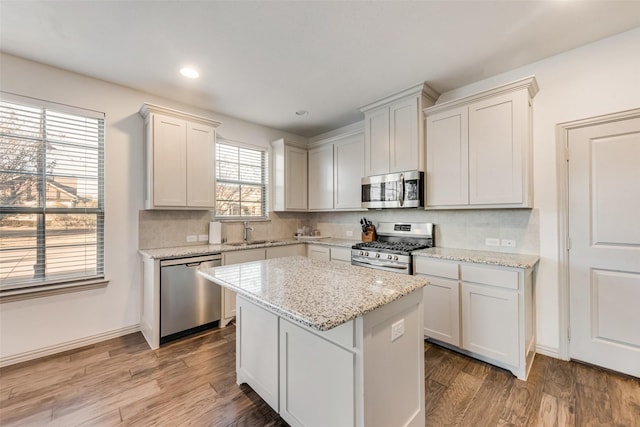 kitchen with light stone counters, white cabinets, stainless steel appliances, and a kitchen island