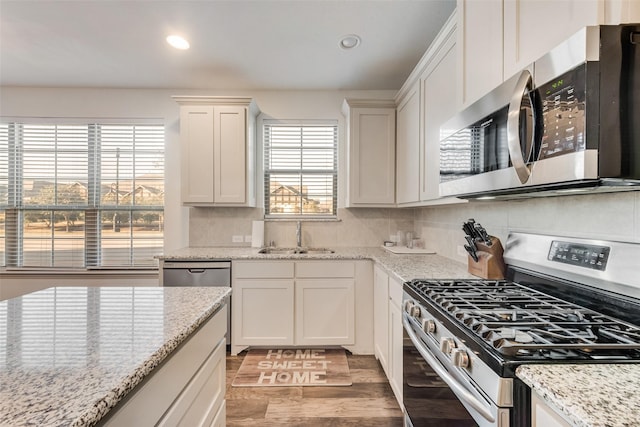 kitchen featuring backsplash, sink, white cabinetry, light stone countertops, and appliances with stainless steel finishes