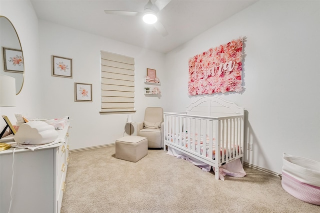 bedroom with ceiling fan, carpet, and a crib