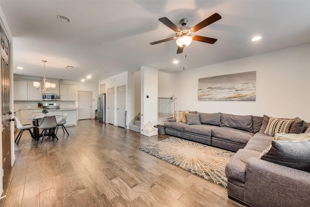 living room featuring light hardwood / wood-style floors and ceiling fan with notable chandelier