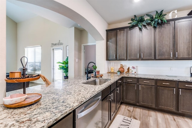 kitchen featuring light wood-type flooring, light stone countertops, stainless steel dishwasher, dark brown cabinetry, and sink