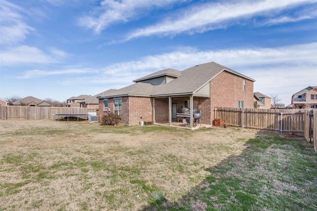 rear view of house featuring central AC, a lawn, and a trampoline