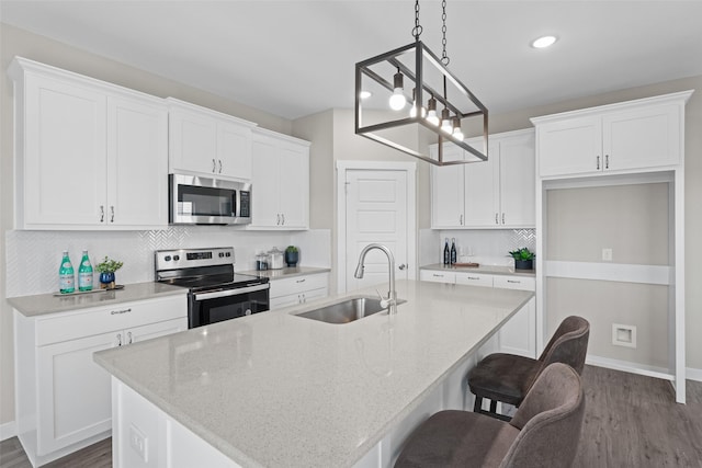 kitchen featuring appliances with stainless steel finishes, a sink, a center island with sink, and white cabinetry