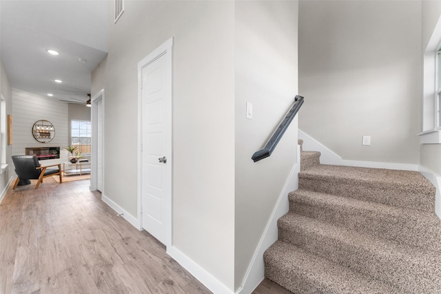 stairway featuring ceiling fan, recessed lighting, a large fireplace, wood finished floors, and baseboards