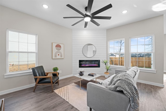 living area with recessed lighting, a fireplace, baseboards, and wood finished floors