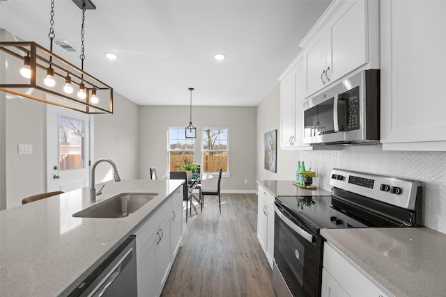 kitchen with pendant lighting, stainless steel appliances, a sink, and white cabinets