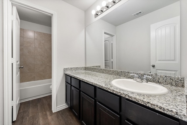 full bathroom featuring toilet, vanity, tiled shower / bath, and hardwood / wood-style floors