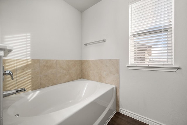 bathroom with a tub to relax in and hardwood / wood-style flooring