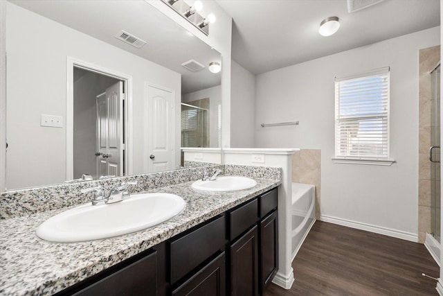 bathroom with independent shower and bath, hardwood / wood-style flooring, and vanity