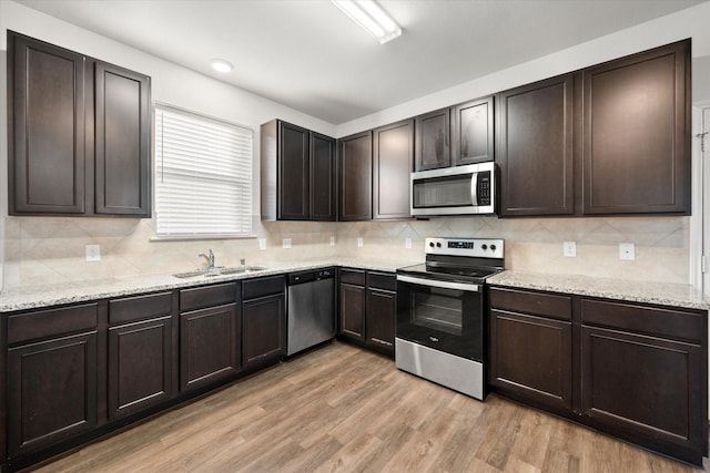 kitchen with appliances with stainless steel finishes, sink, light hardwood / wood-style floors, and dark brown cabinetry