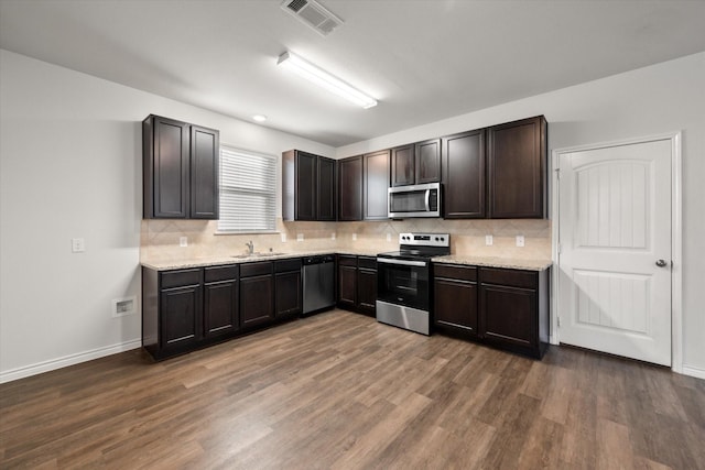 kitchen with decorative backsplash, dark wood-type flooring, dark brown cabinetry, and stainless steel appliances