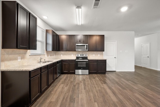 kitchen featuring hardwood / wood-style floors, dark brown cabinetry, stainless steel appliances, sink, and backsplash