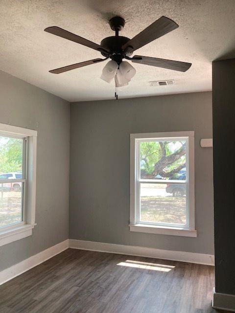 empty room featuring a textured ceiling, ceiling fan, and dark hardwood / wood-style flooring