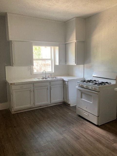 kitchen featuring dark hardwood / wood-style floors, white gas range, white cabinets, and sink