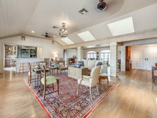 living room with decorative columns, wooden ceiling, light wood-type flooring, lofted ceiling, and ceiling fan with notable chandelier